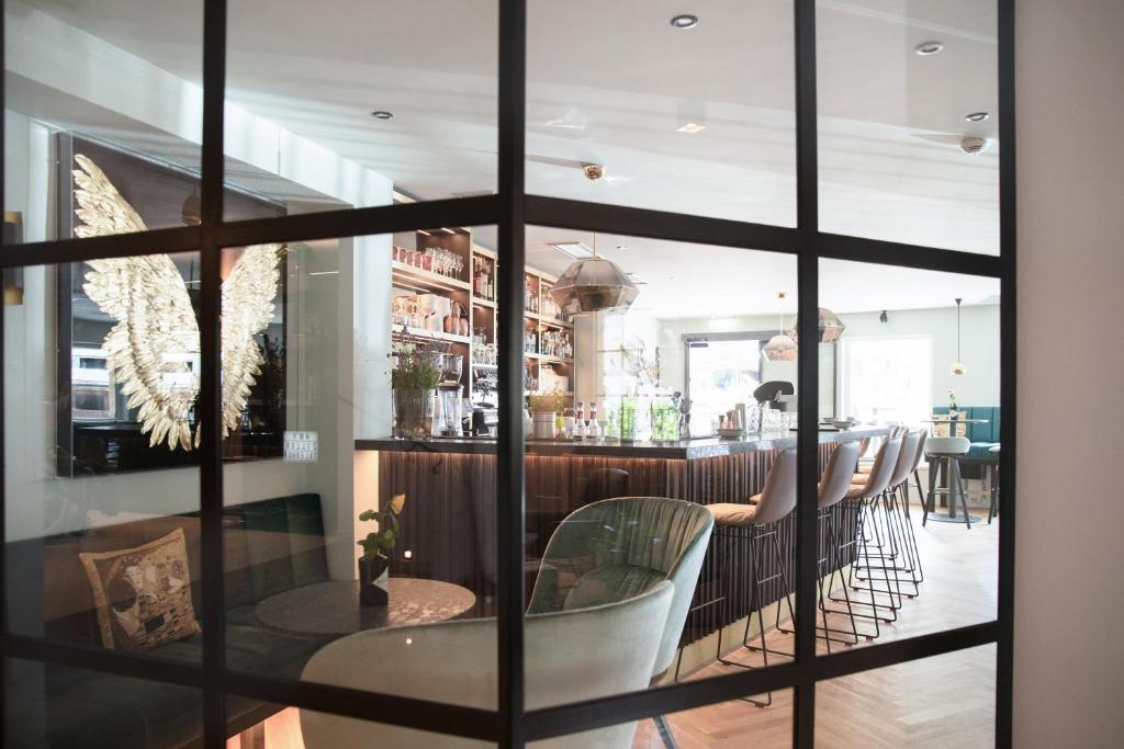 Moderns bārs ar elegantu dizainu un viesmīlīgu atmosfēru, redzams caur stikla sienu. Iekštelpu apgaismojums un stilīgas mēbeles rada patīkamu noskaņu.