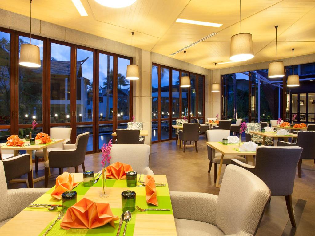 Vairākas galdi un krēsli elegantā restorānā Graceland Khaolak Resort & Spa piekrastē