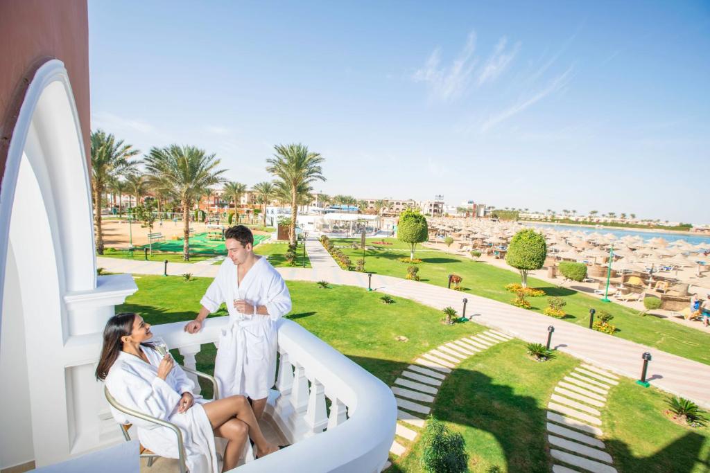 Pāris relaksējas pie Sunrise Garden Beach Resort balkona ar skatu uz piekrasti.