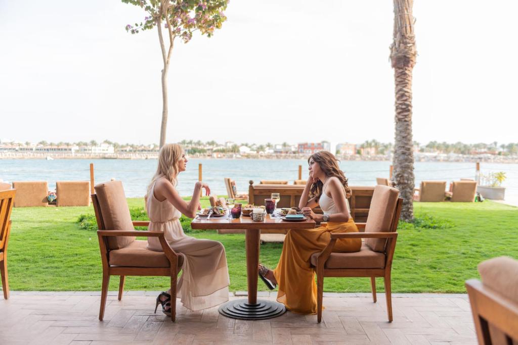 Divas sievietes bauda maltīti pie Sunrise Crystal Bay Resort, piekrastē.