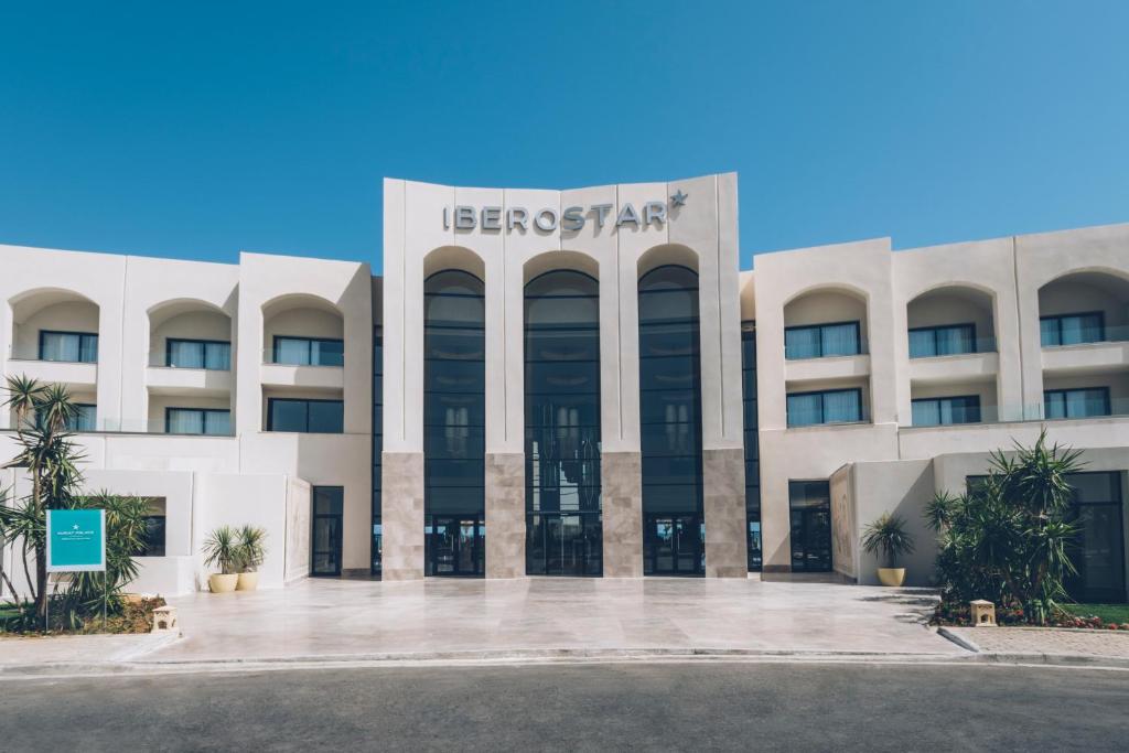 Iberostar viesnīcas moderna fasāde ar skaidru debesu fonu un zaļiem augiem priekšā.