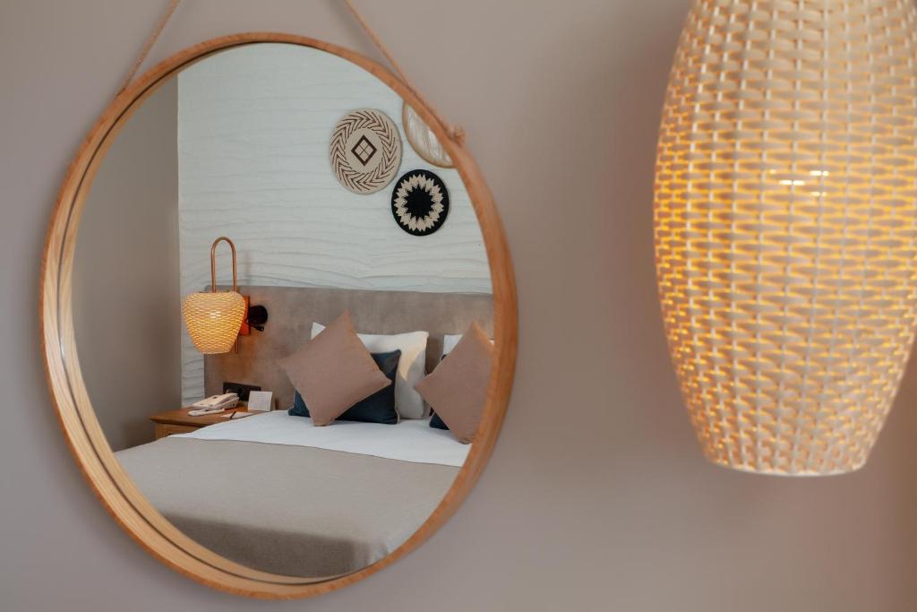 Elegants guļamistabas interjers ar apaļu spoguli un modernu lampu. Mīksti gultas spilveni un dekoratīvi elementi piešķir siltu atmosfēru.