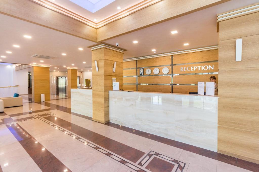 Mūsdienīgs viesnīcas reģistratūras dizains ar koka elementiem un elegantu apgaismojumu. Svaiga un gaumīga atmosfēra, kas rada patīkamu pirmo iespaidu.