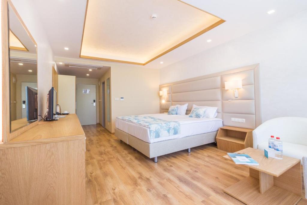 Mūsdienīgs viesnīcas numurs ar divguļamo gultu, koka grīdām un minimālisma dizainu. Telpā ir televizors, naktsgaldiņš un atpūtas zona.