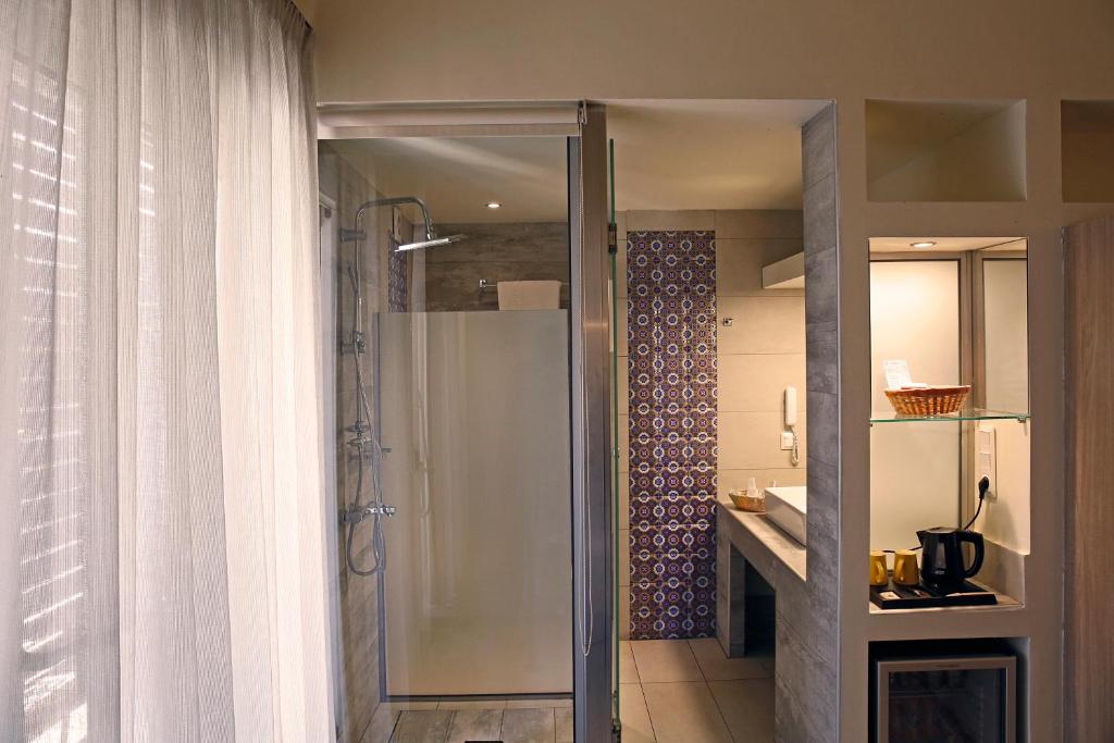 Mūsdienīga vannas istaba ar stikla dušu, gaišām aizkariem un stilīgu flīžu sienu. Interjers ir ērts un pārdomāts, ar kafijas pagatavošanas iespēju un elegantu izskatu.