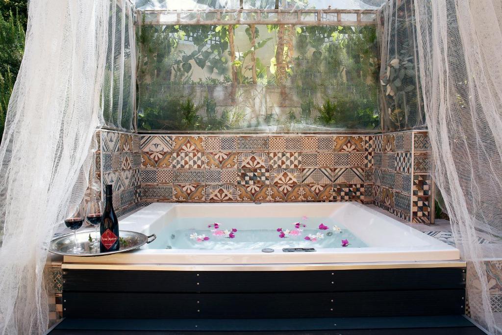 Relaksējoša hidromasāžas vanna ar ziedlapiņām un sarkano vīnu, ieskauta ar elegantu tīklu un dekoratīviem flīzēm. Ideāla vieta atpūtai un romantiskām vakariņām.