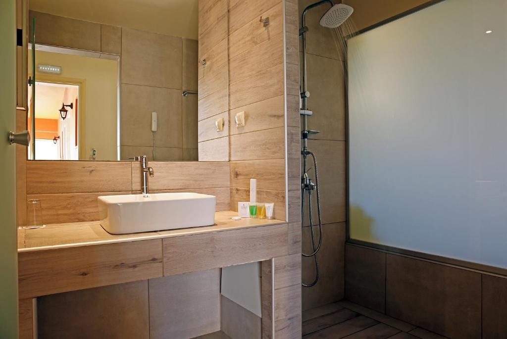 Moderns vannas istabas iekārtojums ar koka apdari, izlietni un dušu, kas veidota ar caurspīdīgu stiklu. Interjers izskatās gaišs un elegants.
