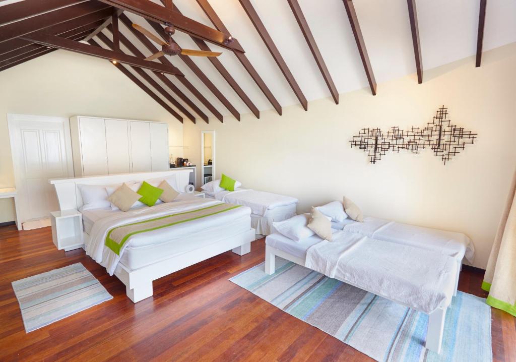 Mūsdienīgs un gaišs viesnīcas numurs ar divām gultām, koka grīdām un augstiem griestiem, rotāts ar krāsainu dekori un mūsdienīgu mākslu uz sienas.