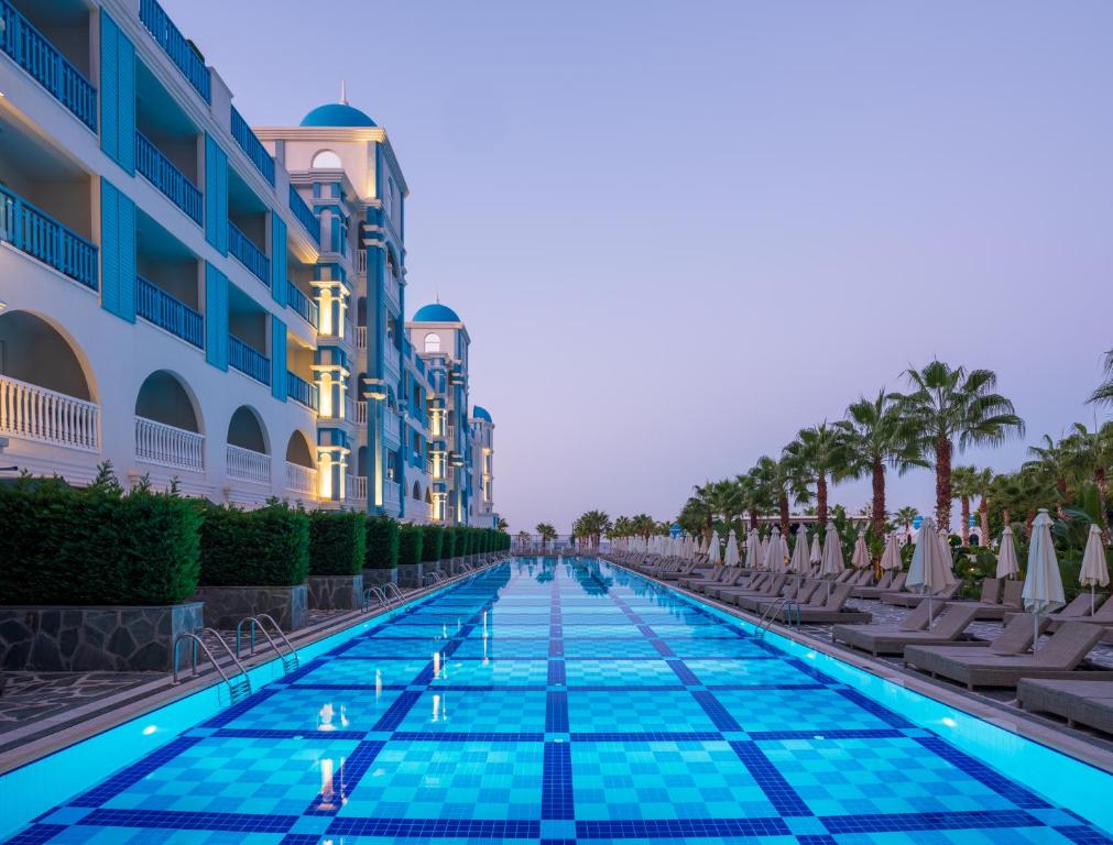 Rubi Platinum SPA Resort & Suites baseins ar palmām un viesnīcas fasādi piekrastē
