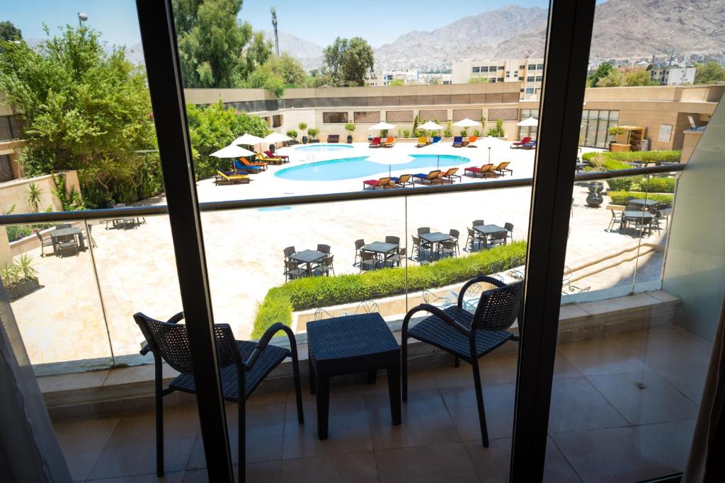 Skats no viesnīcas balkona uz peldbaseinu un apzaļumotu teritoriju, kas iekārtota ar sauļošanās krēsliem un galdiem. Ideāla vieta relaksācijai un atpūtai.