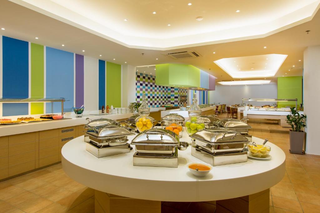 Moderns bufetes stils ar dažādiem ēdieniem, kas pasniegti spīdīgās traukos. Telpa ir gaiša un krāsaina, ar dekoratīvām sienām un ērtām ēdamzonām.