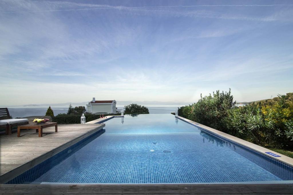 Mūsdienīgs bezgalības baseins ar skatu uz jūru un apkārtējiem augiem, radot mierīgu un relaksējošu atmosfēru. Ideāls atpūtai un brīvdienām.