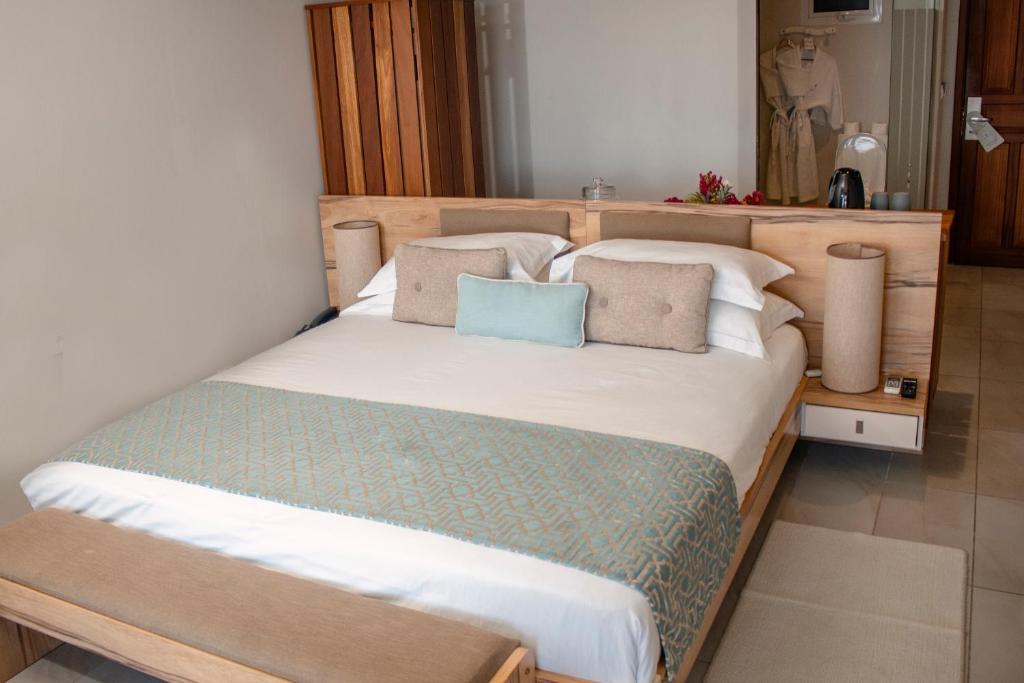 Mūsdienīga guļamistaba ar ērtu gultu un elegantiem dekoratīviem spilveniem, koka mēbelēm un relaksējošu atmosfēru. Interjerā redzami arī gaismas elementi un viesu pakalpojumu stūrītis.