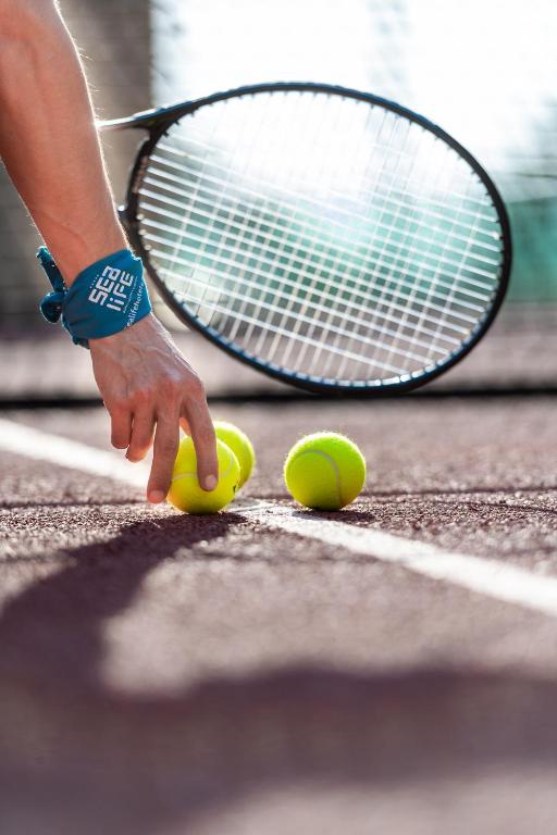 Tennis spēlētājs ņem bumbiņas no laukuma pie Sealife Buket Resort & Beach