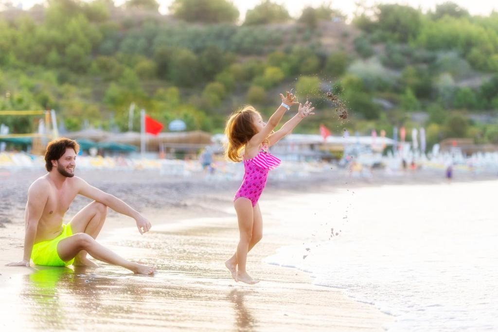 Bērns spēlējas pludmalē pie Sealife Buket Resort & Beach, izsvaidot smiltis.