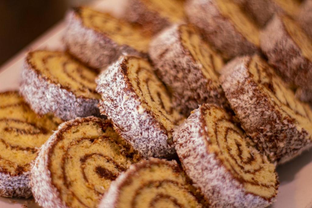 Kokosriekstu rullīši ar šokolādes pildījumu, sakārtoti uz šķīvja. Šie saldie gardumi ir ideāls deserts svinībām vai ikdienai.