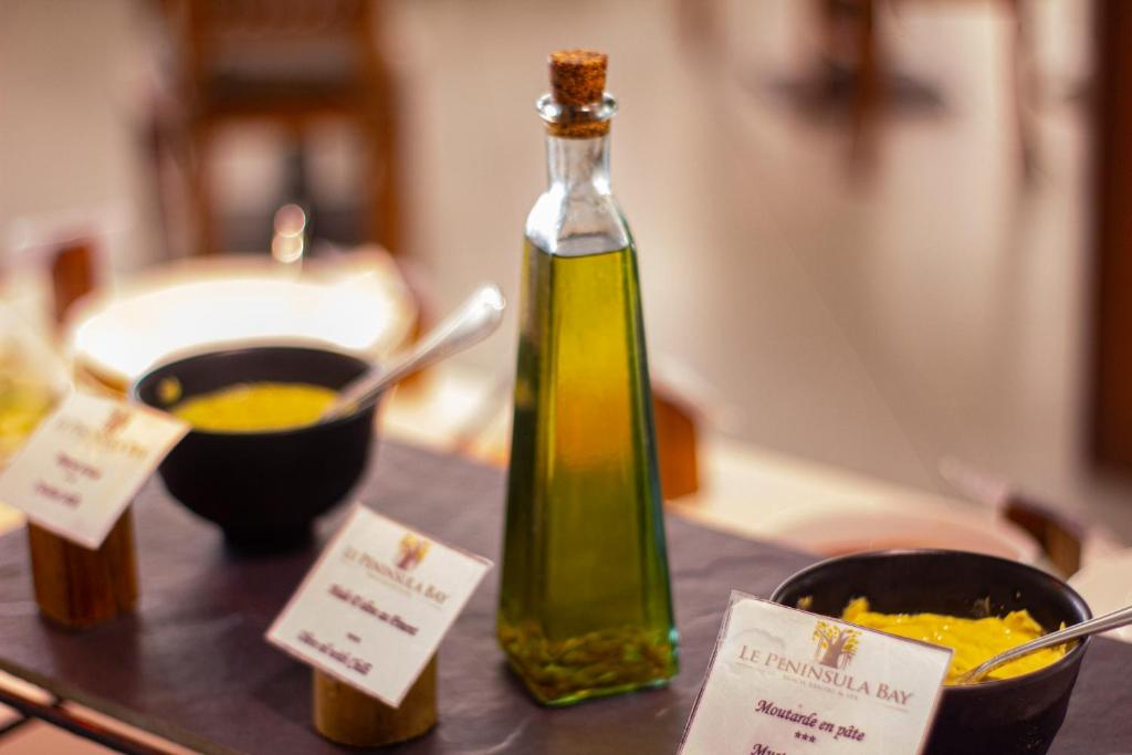 Olīveļļas pudelīte un divi trauki ar mērci uz galda, papildināti ar nosaukumu kartiņām. Ideāli piemērots kulinārijas pieredzei.