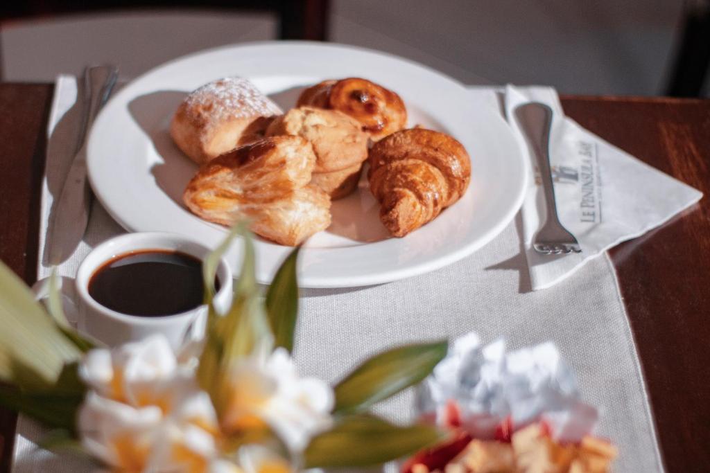 Svaigi cepti konditorejas izstrādājumi kopā ar tasi kafijas, uz galda ar ziediem un salveti.