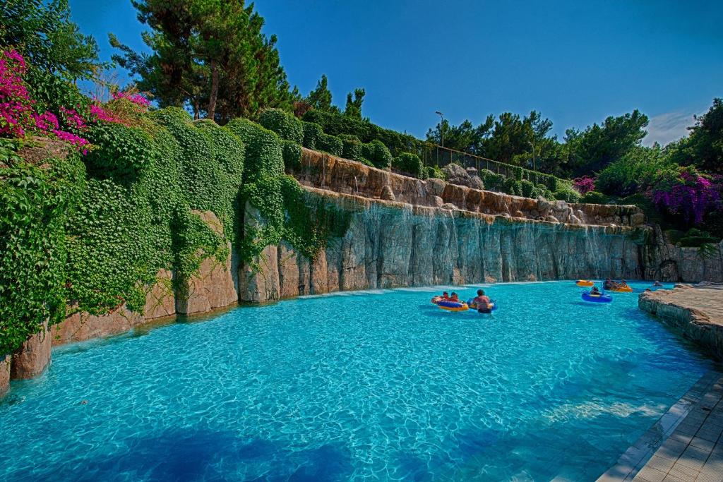 Utopia World Hotel baseins ar ūdens kritumu un ziediem apkārt