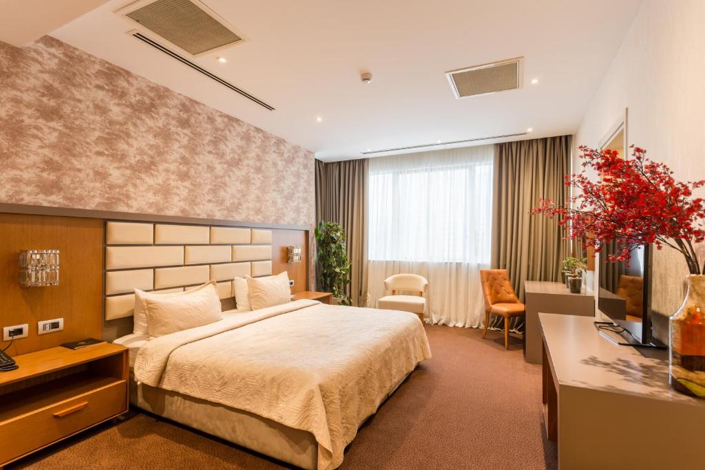 Mūsdienīgs viesnīcas numurs ar plašu gultu, elegantu apdari un dabiskā gaismā piepildītu telpu. Interjeru papildina dekoratīvas ziedu kompozīcijas un komfortablas mēbeles.