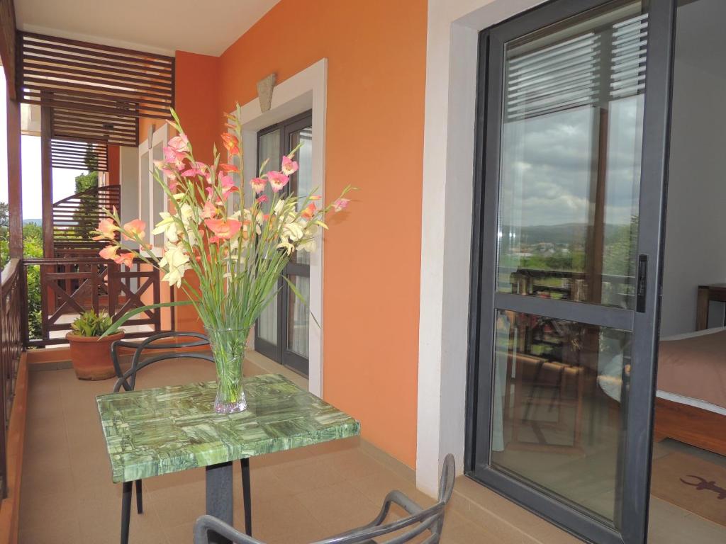 Hotel Plumeria balkons ar skatu uz dārzu un ziediem uz galda.