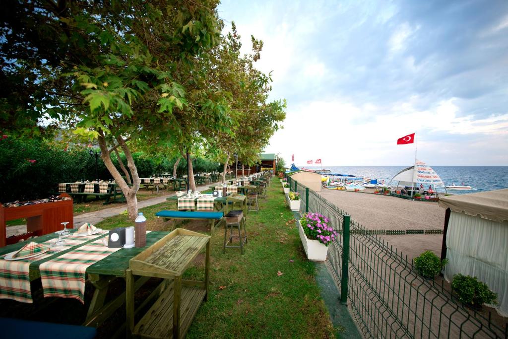 Āra restorāns Limak Limra Hotel & Resort piekrastē ar koka galdiem un krēsliem.