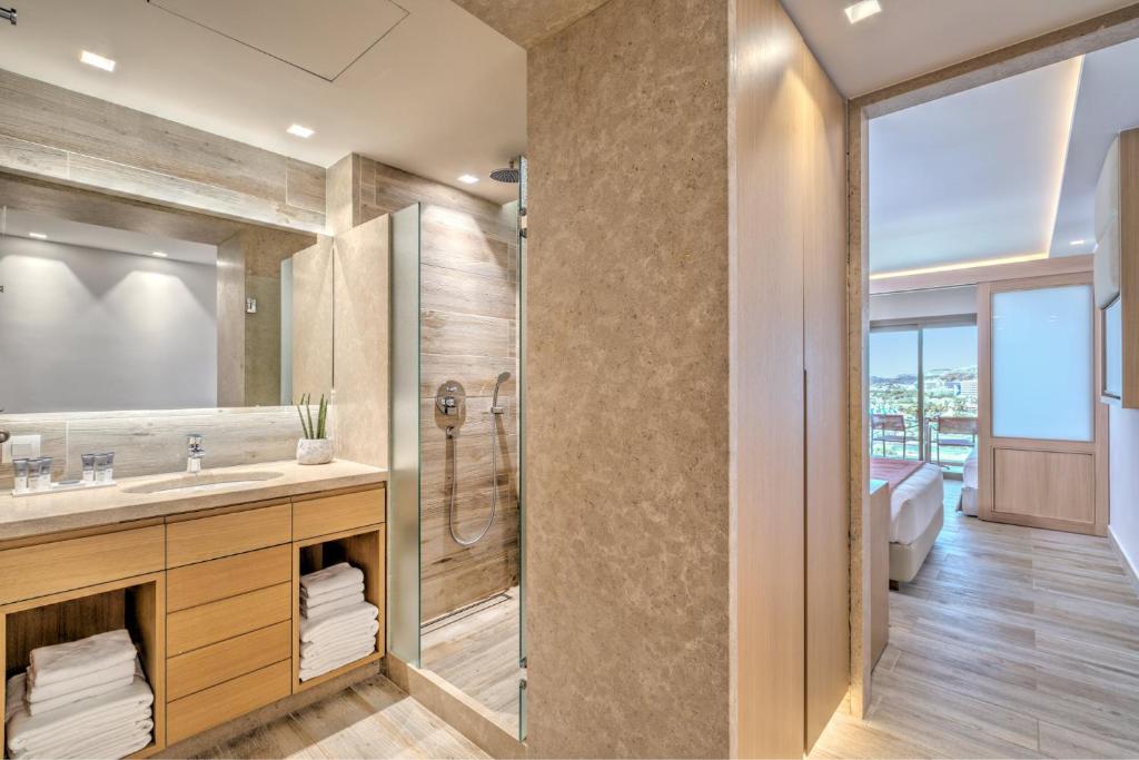 Moderns vannas istabas interjers ar stikla dušu, koka skapīti un neitrālām krāsām, kas rada mierīgu atmosfēru. Gaismas un telpas elementi nodrošina komfortu un eleganci.