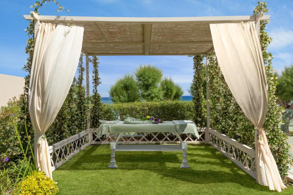 Skaista, ainaviska pergola ar zaļo zāli un ziediem, kas piedāvā mierīgu atpūtas vietu pie jūras.