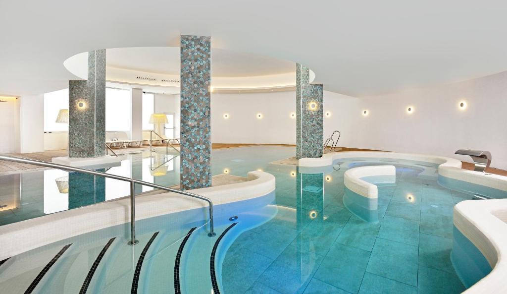 Mūsdienīgs un elegants spa ar ūdens baseinu, ko ieskauj gaismas un mīkstas formas, radot relaksējošu atmosfēru. Ideāla vieta atpūtai un labsajūtai.