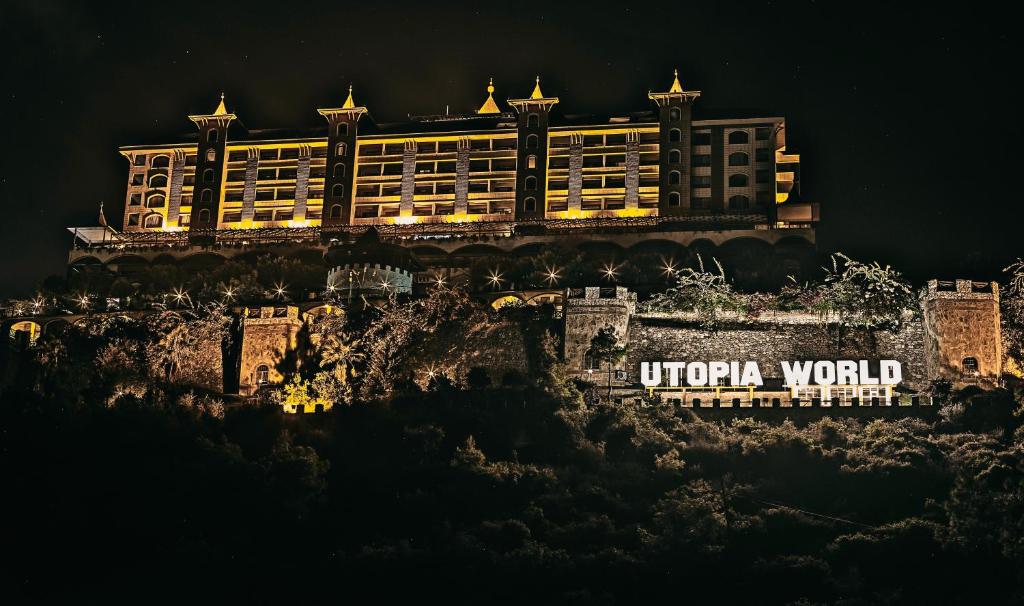 Utopia World viesnīca izgaismota naktī, iespaidīga arhitektūra piekrastē.