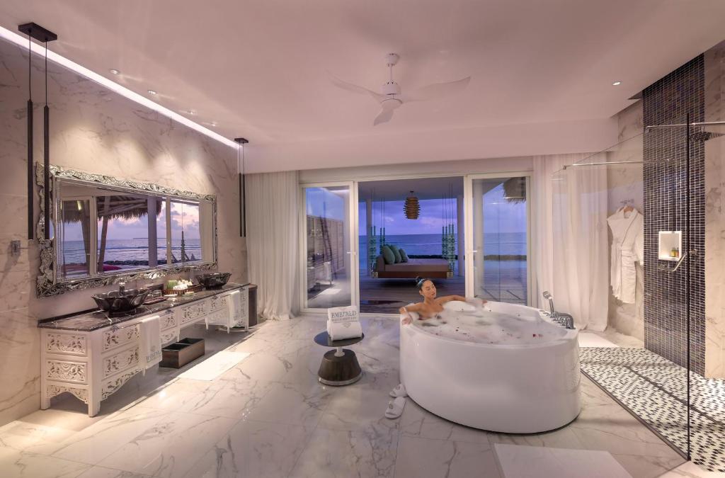 Mūsdienīgs un elegants vannas istabas interjers ar marmora grīdu, burbuļvannu un plašu skatu uz okeānu. Telpā ir stilīgs spogulis un gaiša apgaismojuma elementi, kas rada relaksējošu atmosfēru.