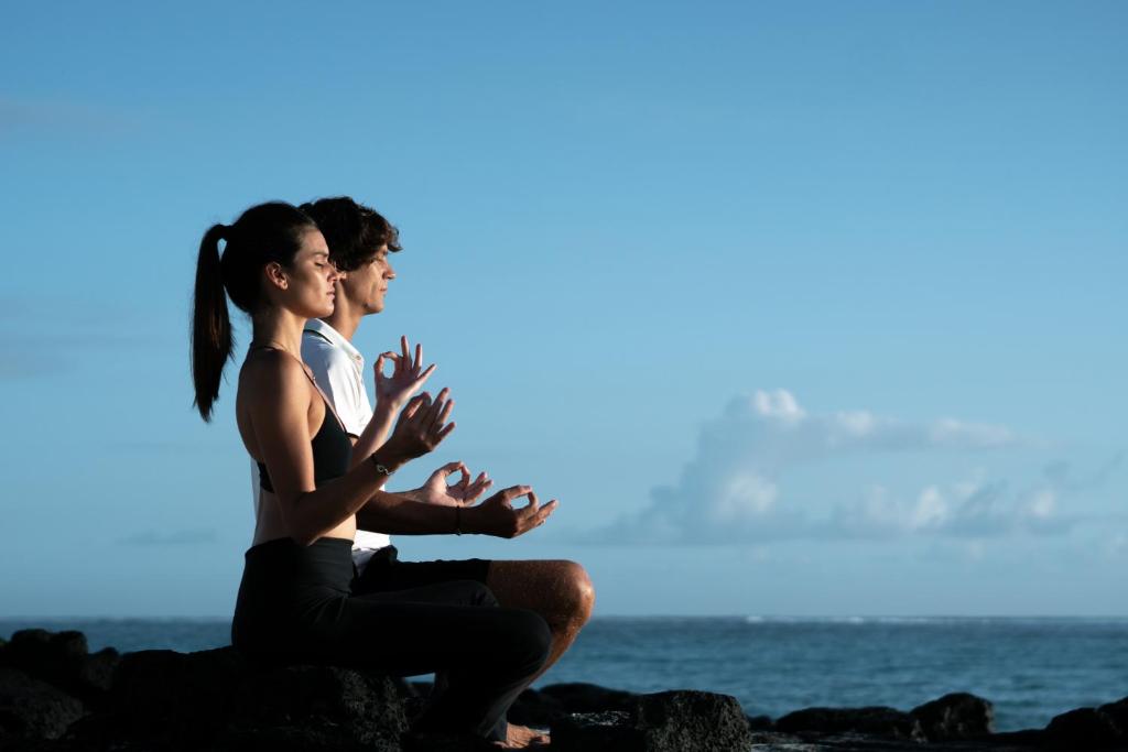 Divi cilvēki meditē uz akmeņiem piekrastē, viesnīcā SALT of Palmar.