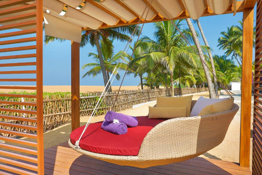 Šī ir šūpuļgulta ar sarkanu spilvenu un violetiem dvieļiem, kas atrodas pludmalē, apkārt palmām un saules gaismai. Ideāla vieta atpūtai un relaksācijai.