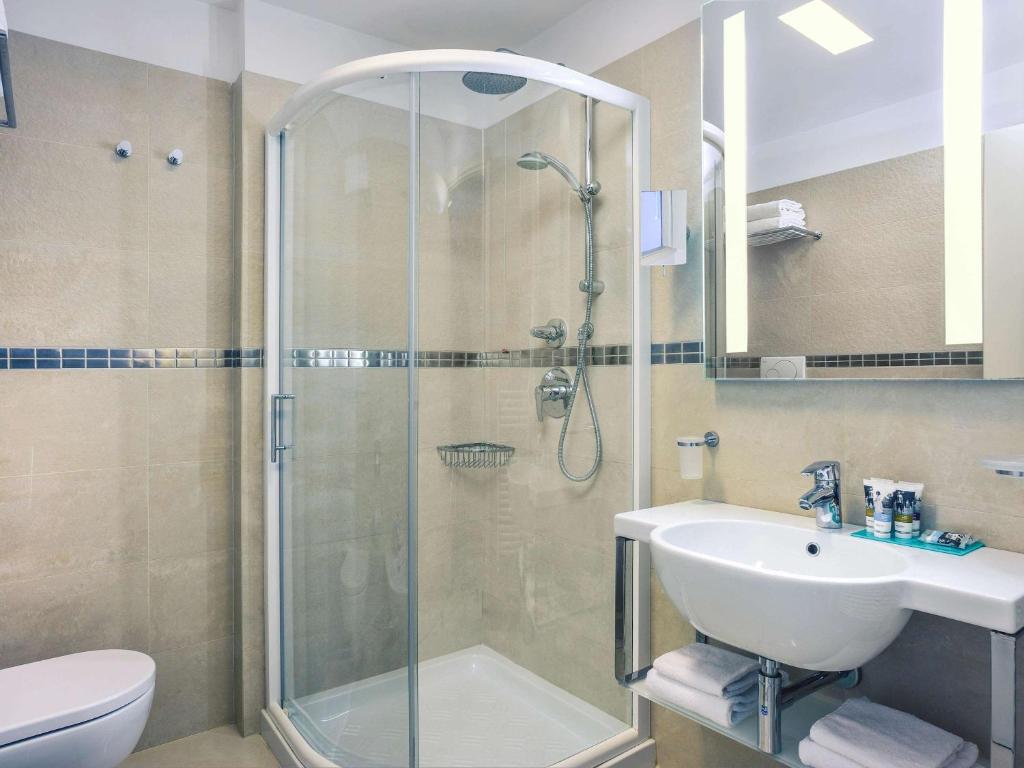 Mūsdienīga un eleganta vannas istaba ar dušu, izsmalcinātu izskatu un modernu apgaismojumu. Vannas istabā ir balta izlietne un higiēnas piederumi.