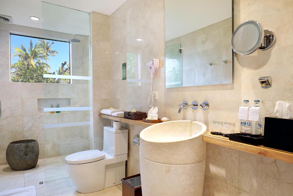 Mūsdienīgs vannas istabas interjers hotelī Legian Beach ar skatu uz palmu kokiem.