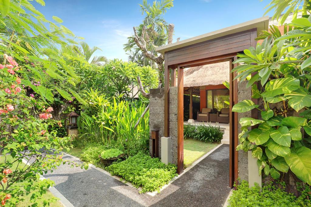 Tropu dārzs pie viesnīcas Legian Beach ar zaļām augiem un ceļu.