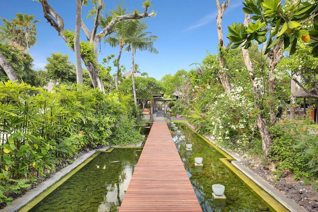 Zaļš dārzs ar koka tiltu un ūdens krātuvi pie viesnīcas Legian Beach.