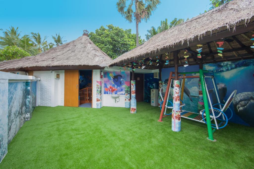 Bērnu rotaļu laukums pie viesnīcas Legian Beach ar zālienu un dekoratīviem elementiem.