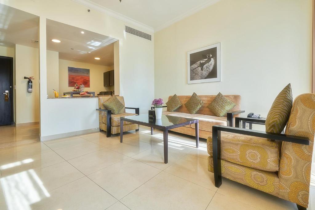 Mūsdienīgs viesnīcas numurs Bahi Ajman Palace ar viesistabu un ērtām mēbelēm.