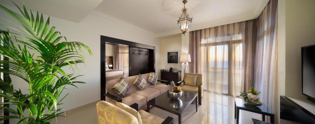 Eleganta viesnīcas Bahi Ajman Palace numura viesistaba ar dabu un mājīgumu.