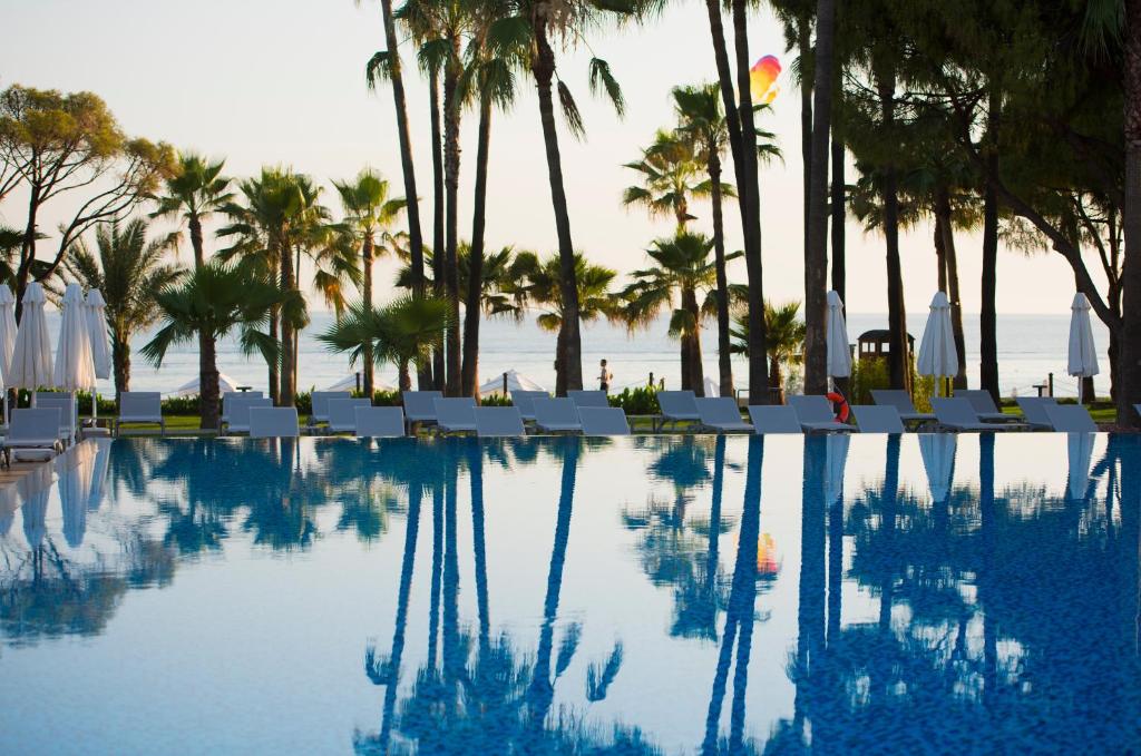 Acanthus & Cennet Barut Collection baseins ar palmām un jūru fona