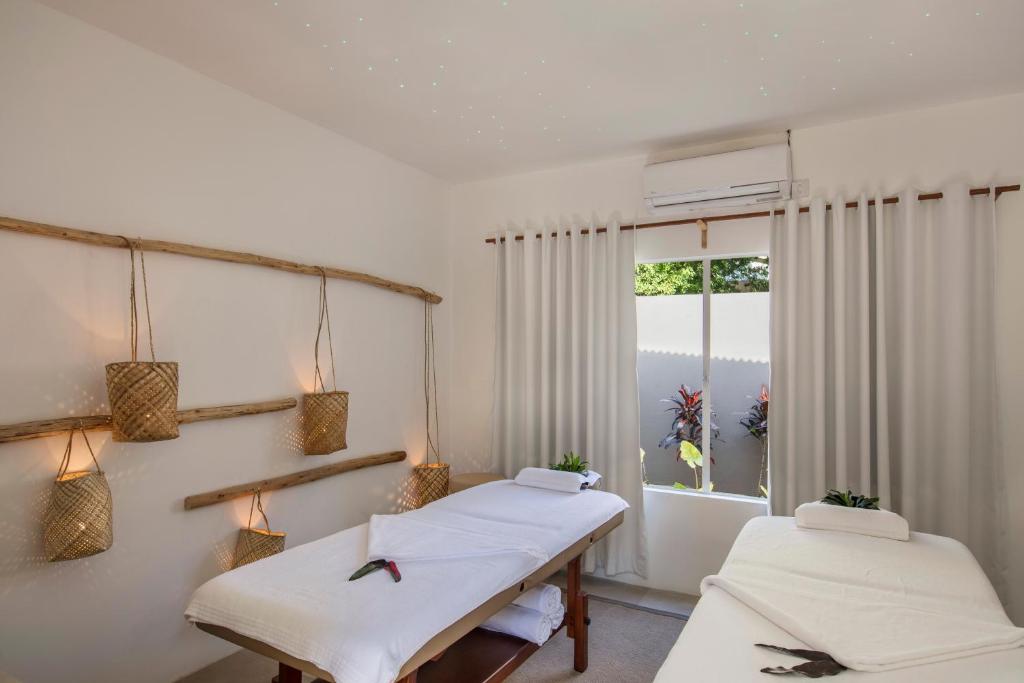 Masažu telpa Veranda Tamarin Hotel & Spa ar divām gultām un dabīgiem elementiem.