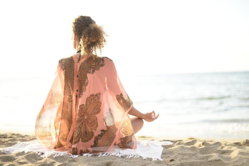 Sieviete meditē pludmalē pie Veranda Tamarin Hotel & Spa