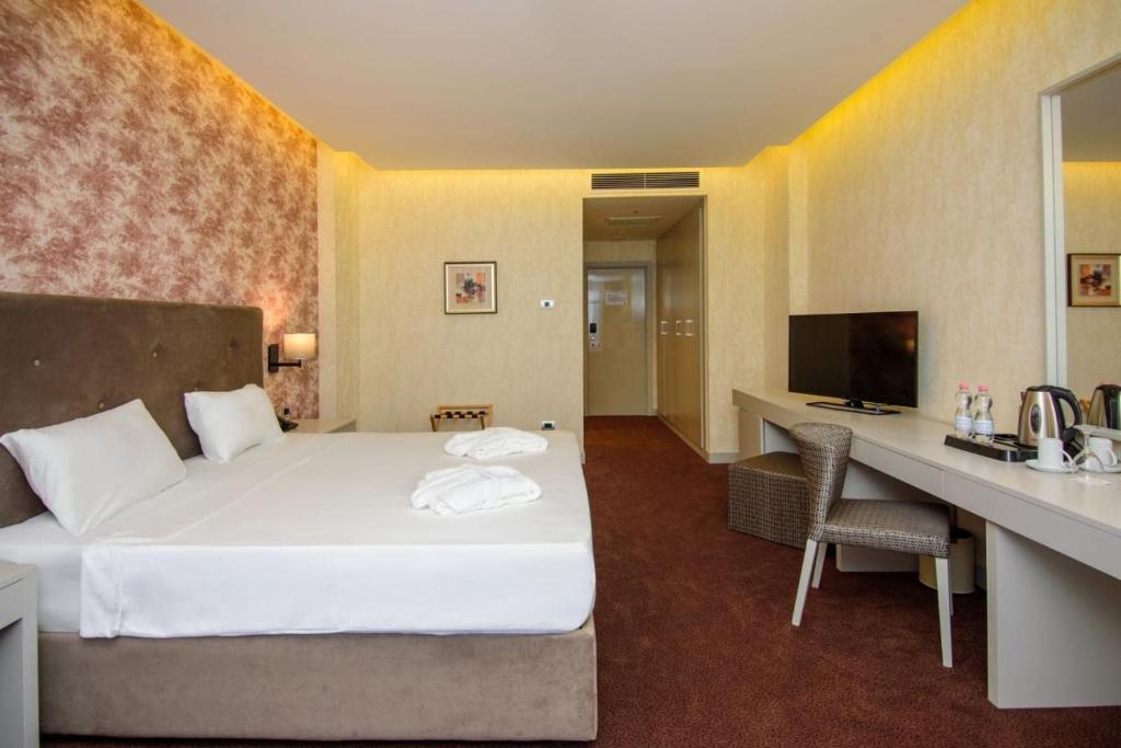 Mūsdienīgs viesnīcas numurs ar divvietīgu gultu, televizoru un rakstāmgaldu. Interjers ir elegants, ar siltām krāsām un apgaismojumu.