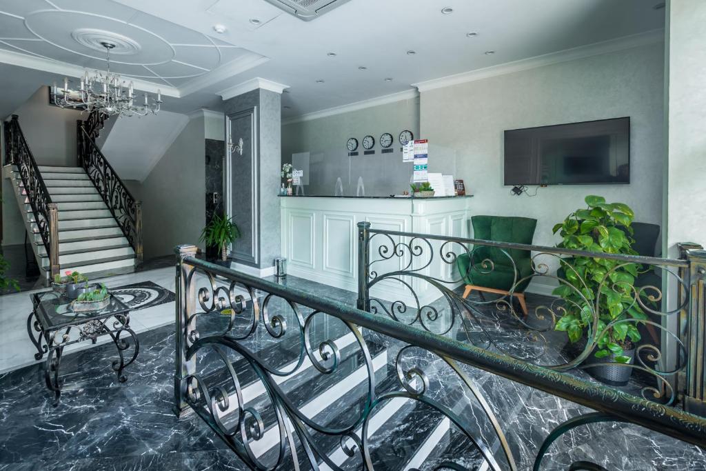 Mūsdienīgs viesnīcas reģistratūras un uzņemšanas zona ar elegantu dizainu, melnu marmora grīdu un stilīgu kāpņu konstrukciju. Izcila apgaismojuma un zaļo augu kombinācija rada patīkamu atmosfēru.