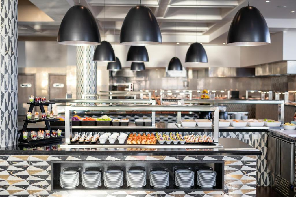 Mūsdienīgs bufetes restorāns ar elegantiem melnajiem gaismekļiem, kurā piedāvāti dažādi ēdieni un deserti. Interjers raksturos stilīgas flīzes un kārtīgi sakārtotas ēdienu stacijas.