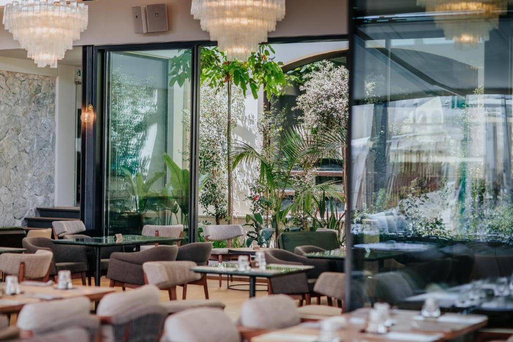 Mūsdienīgs restorāns ar plašu stiklotu telpu un zaļām augiem, radot patīkamu un gaišu atmosfēru. Eleganti galdi un krēsli piedāvā komfortablu atpūtu.