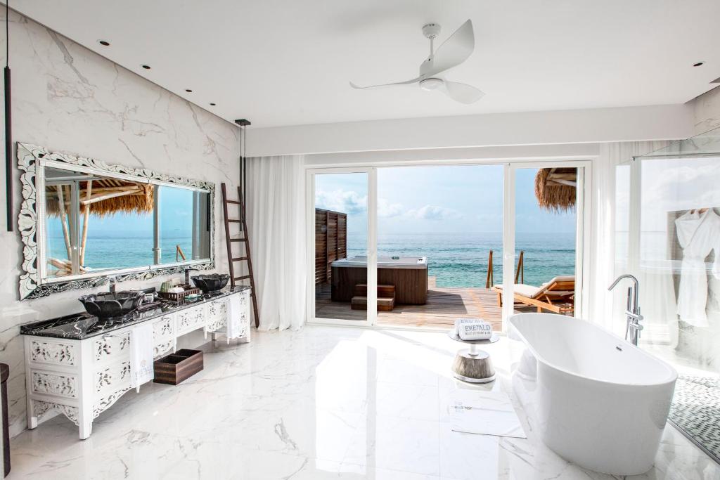 Mūsdienīgs vannas istabas interjers ar skatu uz okeānu, eleganta balta vannas istaba un liela spoguļa atspoguļojums. Gaismas un plašuma sajūta, kas rada relaksējošu atmosfēru.