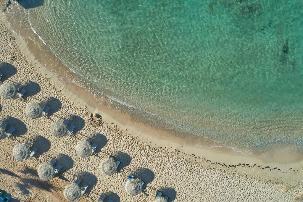 Pludmale pie Mare Ayia Napa ar saulessargiem un kristāldzidru ūdeni.