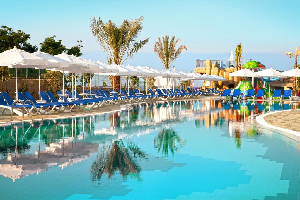 Numa Bay Exclusive Hotel baseins ar sauļošanās krēsliem un palmu kokiem